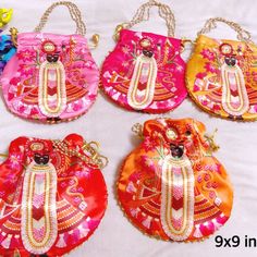 four different colored purses with chains hanging from them on a white tablecloth background