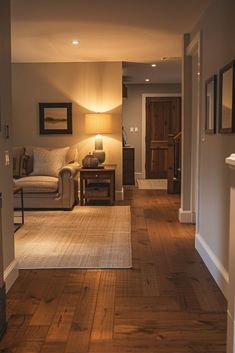 a living room filled with furniture and a lamp on top of a hard wood floor