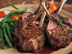 two steaks on a plate with green beans and carrots