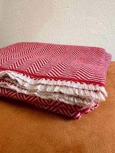 red and white chevroned blanket folded on top of an orange surface with a white wall in the background