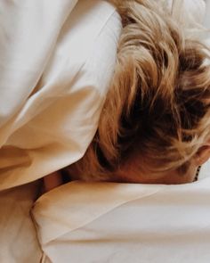 a woman laying in bed with her head under the covers