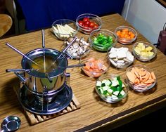 a wooden table topped with bowls filled with different types of food next to a blender