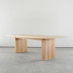 a wooden table sitting on top of a cement floor next to a white wall in an empty room