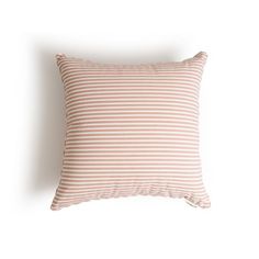 a pink and white striped pillow on a white wall