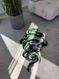 a snake wrapped around a plant in the middle of a room with white walls and flooring