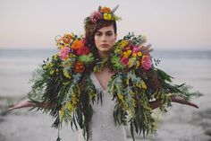 a woman with flowers in her hair and wreaths around her neck on the beach