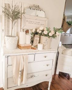 a white dresser with flowers and candles on it