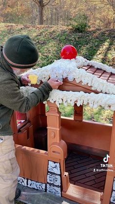 a young boy is playing with a fake house made out of wood and plastic material