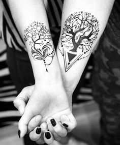 two people are holding hands with tattoos on their arms and one has a tree in the middle