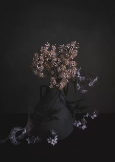 a vase filled with lots of flowers on top of a black table next to a snake