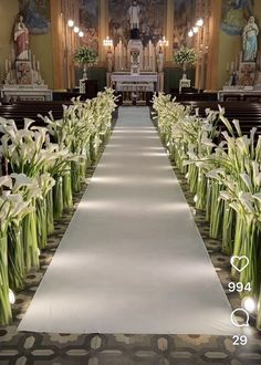 the aisle is lined up with flowers and candles on each side, along with pews