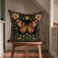 a decorative butterfly pillow sitting on top of a wooden stool