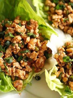 lettuce wraps filled with meat and vegetables on a white plate, ready to be eaten