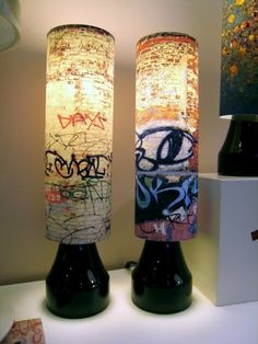 two vases with graffiti on them are next to a lamp that is turned on