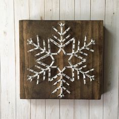 a snowflake made out of white sticks on a wooden board against a wall