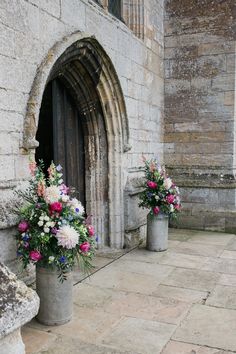 two vases with flowers are sitting on the side of a building near a doorway