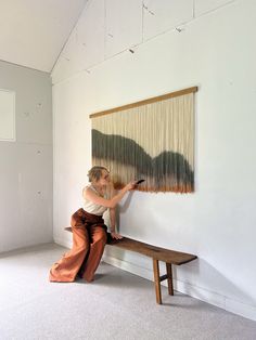 a woman is sitting on a bench and weaving