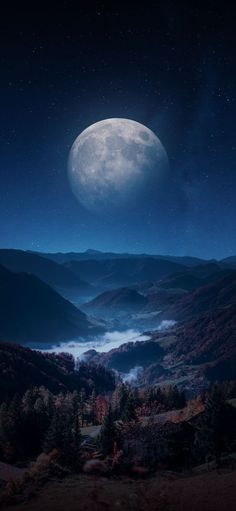 the full moon is seen over mountains and valleys