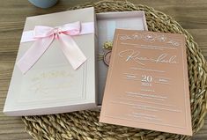 an open box with a pink ribbon on it next to a white and gold wedding card