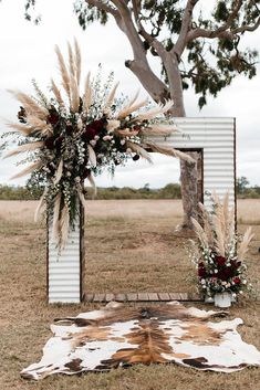 the wedding arch is decorated with pampas grass and burgundy flowers from margobellas