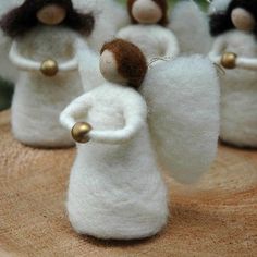 several small white angels with brown hair on top of a wooden table next to green plants