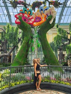 two women standing in front of a fake flower display at the gardens by the bay