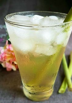 a tall glass filled with ice sitting on top of a table next to pink flowers