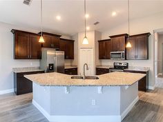 an empty kitchen with granite counter tops and stainless steel appliances in the center, surrounded by wooden cabinets