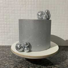 there is a silver cake with three shiny balls on the top and two smaller ones in the middle