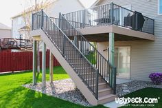 an outside view of a two story house with a metal stair case and green grass