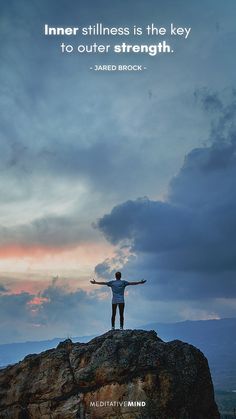 a man standing on top of a large rock with his arms outstretched in the air