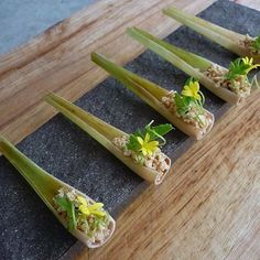 four pieces of sushi are arranged on a cutting board with green onions and celery