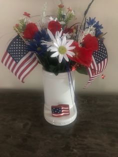 a patriotic flower arrangement in a white vase