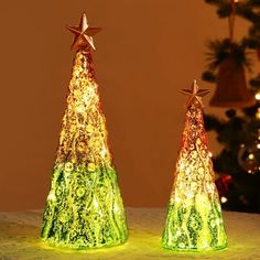 two lighted christmas trees sitting on top of a table