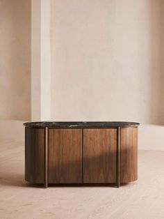 a round table with black marble top in an empty room by a wall and wooden floor