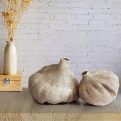 two vases sitting on top of a wooden table next to a white brick wall