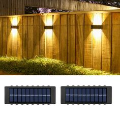 two solar powered lights on the side of a wooden fence next to grass and bushes