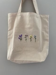 a white bag with three flowers embroidered on it