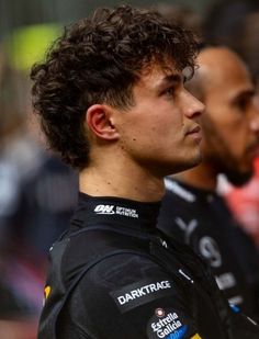 a close up of a person wearing a racing suit and looking off to the side