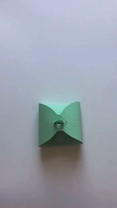 an origami bow hanging on the wall in front of a white wall with a light green background