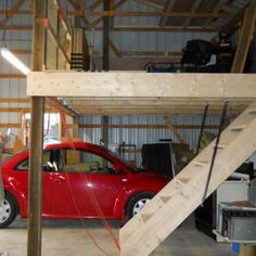 a red car parked in a garage next to a stair case on the side of a building