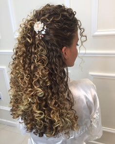 the back of a woman's head with curly hair and flowers in her hair