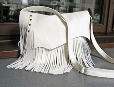 This bag is made from natural white leather, which gives it a clean and elegant look. Being fully handmade, it likely has unique details and craftsmanship. The color "natural white" suggests a neutral tone that can complement various outfits. Perfect for everyday use, it's versatile and functional. Dimensions: height: 21 cm (6 in) max width: 27 cm (10.5 in) strap: max 130 cm (51 in) Hobo bag made from genuine first class leather. *Zippered *Unlined * Includes internal pocket for mobile phone and other small items. Important note: The flap on the bag may differ slightly because of the natural edge of the leather used to sew it. Dimensions: height: 21 cm (6 in) max width: 27 cm (10.5 in) strap: max 130 cm (51 in) * Includes internal pockets for mobile phone and other small items. White Tassel Bags For Everyday Use, White Everyday Bags With Tassels, White Shoulder Bag With Tassels For Daily Use, White Tassels Bag For Everyday Use, White Tassel Shoulder Bag For Daily Use, White Fringe Shoulder Bag For Everyday Use, White Leather Lined Crossbody Bag, White Leather Bags With Leather Trim, White Rectangular Shoulder Bag With Fringe