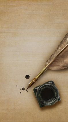 a feather quill and ink pen on a wooden surface with some black stuff around it