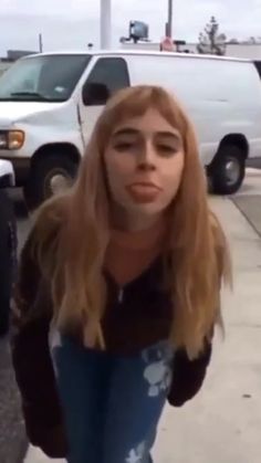 a woman with long hair is standing in front of a white van and looking at the camera