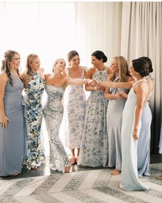 a group of women standing next to each other in front of a window holding hands