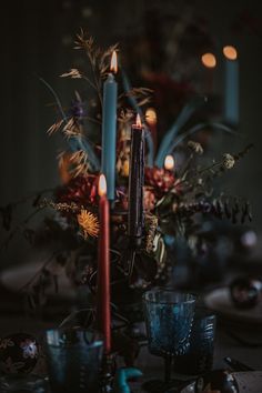 a table topped with candles and flowers on top of a wooden table covered in dishes