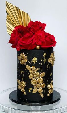 a black and gold decorated cake with red flowers