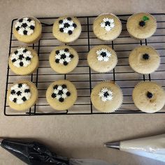 cupcakes with black and white frosting sitting on a cooling rack next to a pair of scissors