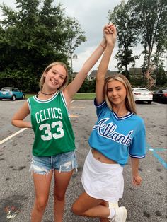 two girls in sports jerseys are holding their hands up and posing for the camera with each other